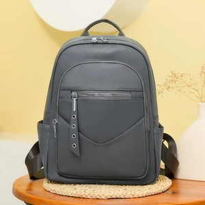 Close-up of dark grey PU leather backpack showing premium pebble grain texture and zippers