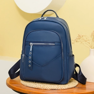 Detail of dark blue soft PU leather backpack featuring multiple metal zipper compartments