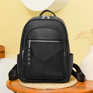 Close-up of litchi texture black PU leather backpack with silver zippers on a table