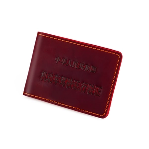 Close-up of dark red vintage leather driver's license cover with orange stitching detail