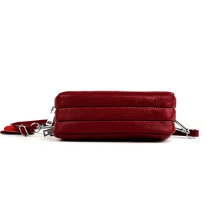 Détail du sac bandoulière en cuir rouge foncé avec trois compartiments zippés et texture grainée