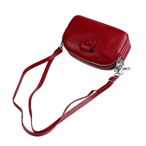 Détail du sac bandoulière en cuir grainé rouge avec double fermeture éclair et métal