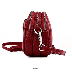 Gros plan d'un sac bandoulière en cuir rouge avec triple fermeture éclair et texture