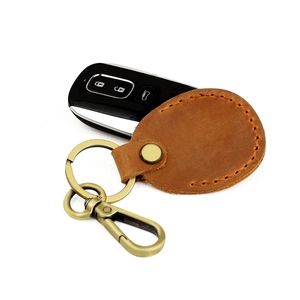 Close-up of brown leather key case with visible stitching and metal D-ring buckle detail