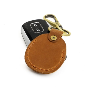 Detail of vintage brown leather AirTag case with manual stitching and brass carabiner