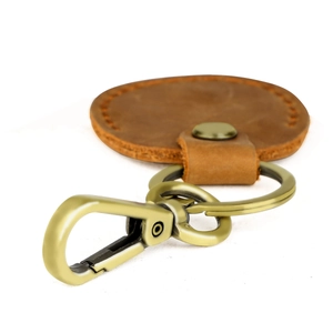 Macro view of vintage brown leather key fob with brass spring lobster clasp and metal snap