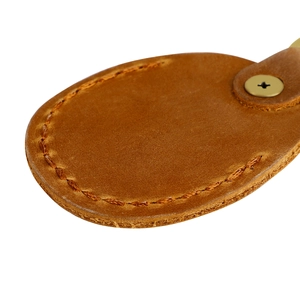 Macro shot of brown leather protective cover with fine stitching and gold metal screw