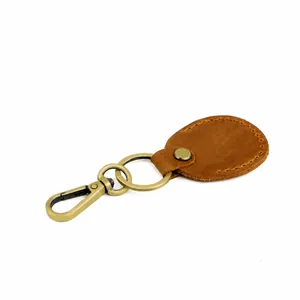Close-up of vintage brown leather keychain with orange stitching and bronze metal clasp
