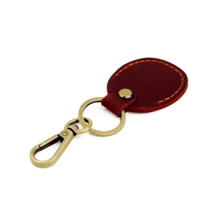 Detail of burgundy leather keychain with yellow stitching and sturdy golden hardware clasp