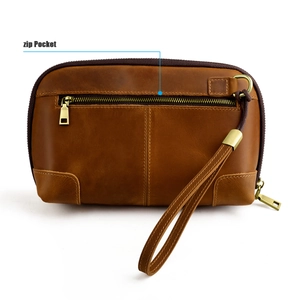 Close-up of vintage brown leather clutch bag showing rear zip pocket and brass hardware