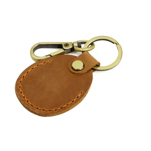 Vintage brown leather AirTag keychain with retro bronze hardware and orange stitching