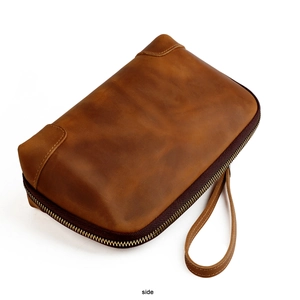 Side view of vintage crazy horse leather clutch bag with wrist strap and metal zipper