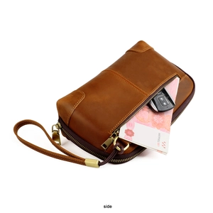 Detailed side view of vintage crazy horse leather clutch bag with wristlet and outer pocket
