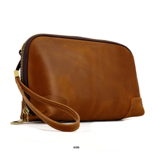 Side view of brown leather clutch bag with premium metal zipper and wrist strap detail