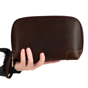 Macro shot of dark brown vintage leather pouch with zipper and orange stitching detail