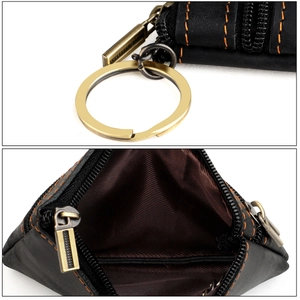 Macro detail of black leather key pouch featuring orange contrast stitching and brass hardware