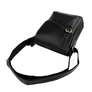 Detail of black leather crossbody bag with white stitching and gold metal buckle