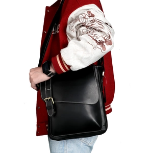Close-up of black crazy horse leather messenger bag with white contrast stitching detail