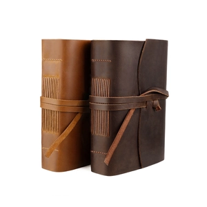 Detail of two handmade vintage leather journals with exposed stitching and wrap closure