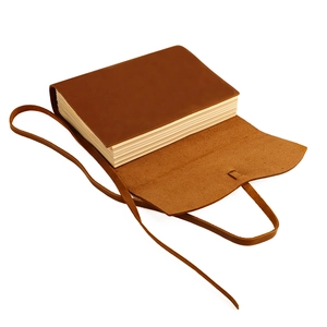Close-up of vintage leather journal with thick cream paper and a wrap-around tie closure