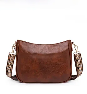 Dettaglio della borsa vintage marrone con ecopelle martellata e ampia tracolla in tessuto
