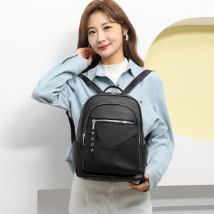 Detailed shot of a black pebbled leather backpack with silver zippers on a female model