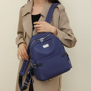 Detailansicht eines dunkelblauen Nylon-Rucksacks getragen von einem Modell im Trenchcoat