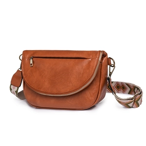Close-up of caramel faux leather saddle bag with colorful geometric woven wide shoulder strap