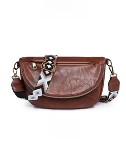 Close-up of vintage brown moon-shaped crossbody bag with patterned woven strap