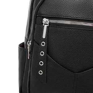 Detail of black pebbled leather backpack showing silver zippers and metal ring pulls