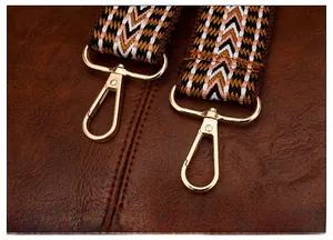 Dettaglio della fibbia dorata rimovibile su borsa vintage marrone con tracolla intrecciata