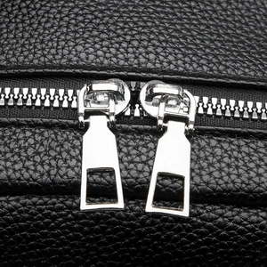 Close-up of black litchi grain PU leather backpack with dual silver metal zippers