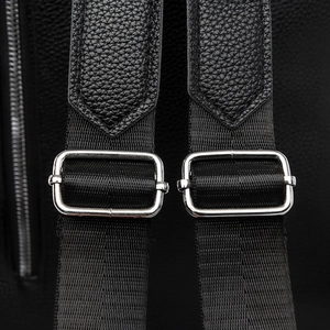 Close-up of adjustable straps and silver metal buckles on black leather backpack