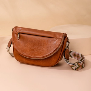 Detail of vintage brown leather crossbody bag with ethnic patterned woven shoulder strap