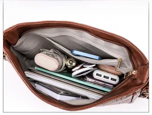 Interno spazioso di una borsa marrone con tasca zip e vari oggetti quotidiani