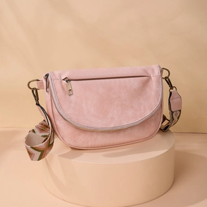 Detail of pink saddle bag featuring vintage hardware and colorful geometric woven strap