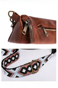 Detail of vintage brown leather sling bag with resin metal zipper and colorful woven strap