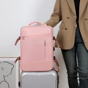 Pink business travel backpack with luggage strap secured on a silver suitcase handle