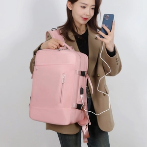 Pink waterproof laptop backpack side detail showing USB charging port and zipper pockets