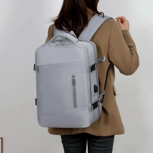 Detail showing the USB charging port and side buckle of the grey business travel backpack