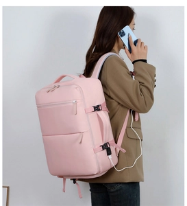 Detail showing the external USB charging port of the pink travel backpack charging a phone