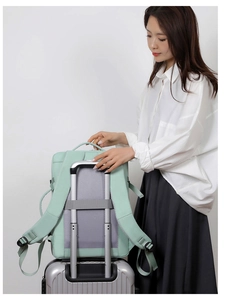 Mint green travel backpack showing the trolley sleeve feature on a metal suitcase