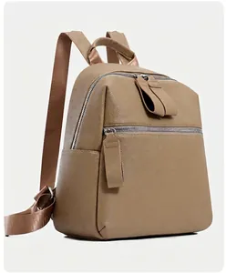 Detail of khaki PU leather backpack showing fine lychee grain texture and front zipper pocket