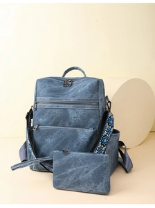Dettaglio dello zaino in tela blu lavato con tracolla ricamata e mini pochette coordinata