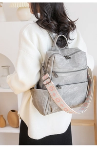 Zaino grigio vintage con tracolla ricamata indossato da modella in interno