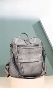 Detail of grey PU leather backpack featuring woven strap and multi-zippered pocket design