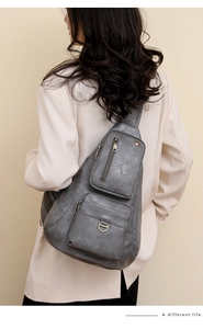 Détail du sac bandoulière gris vintage avec doubles poches zippées porté par un mannequin