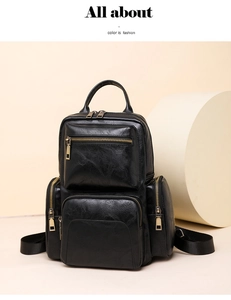 Close-up of black PU leather backpack with multiple zipper pockets and gold hardware