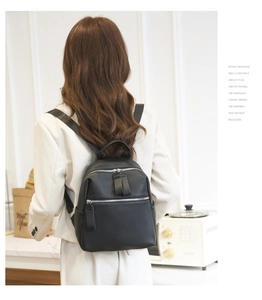 Detail of black backpack with litchi texture and double front zippers on model