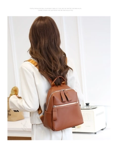 Rear view of woman wearing brown pebbled leather backpack with silver zippers in bright room